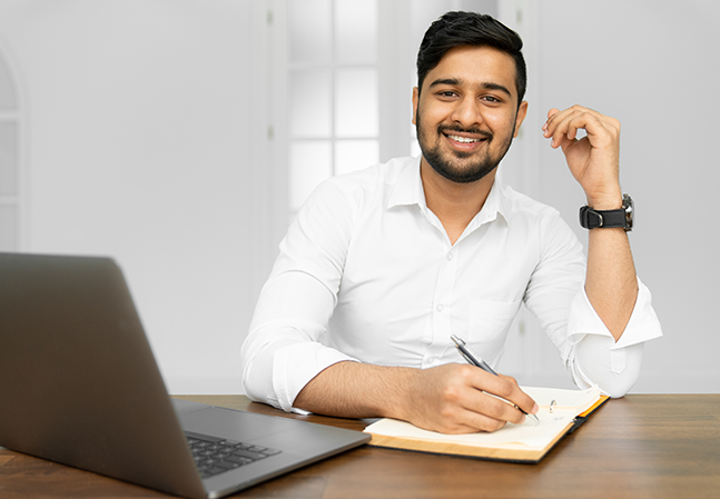 Man smiling at his desk with laptop and notepad
