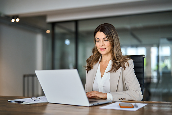 Middle-aged woman in her office typing on her laptop