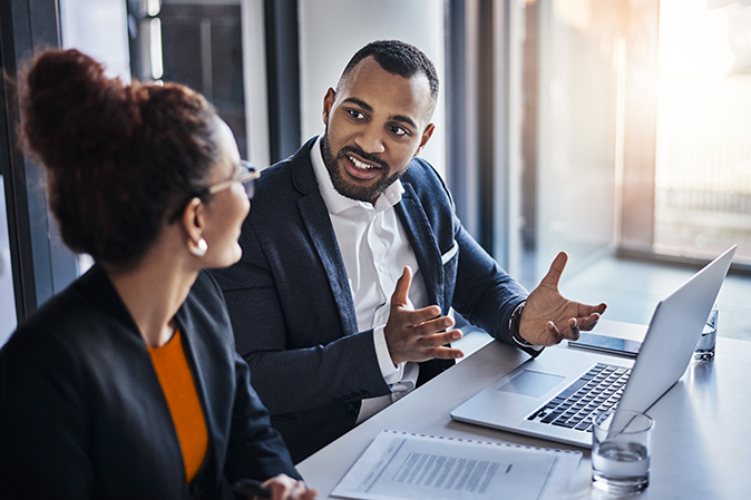 Meeting, laptop and performance review with business people in office together for project management or teamwork. Document, discussion and idea with man, woman or workplace for b2b collaboration.